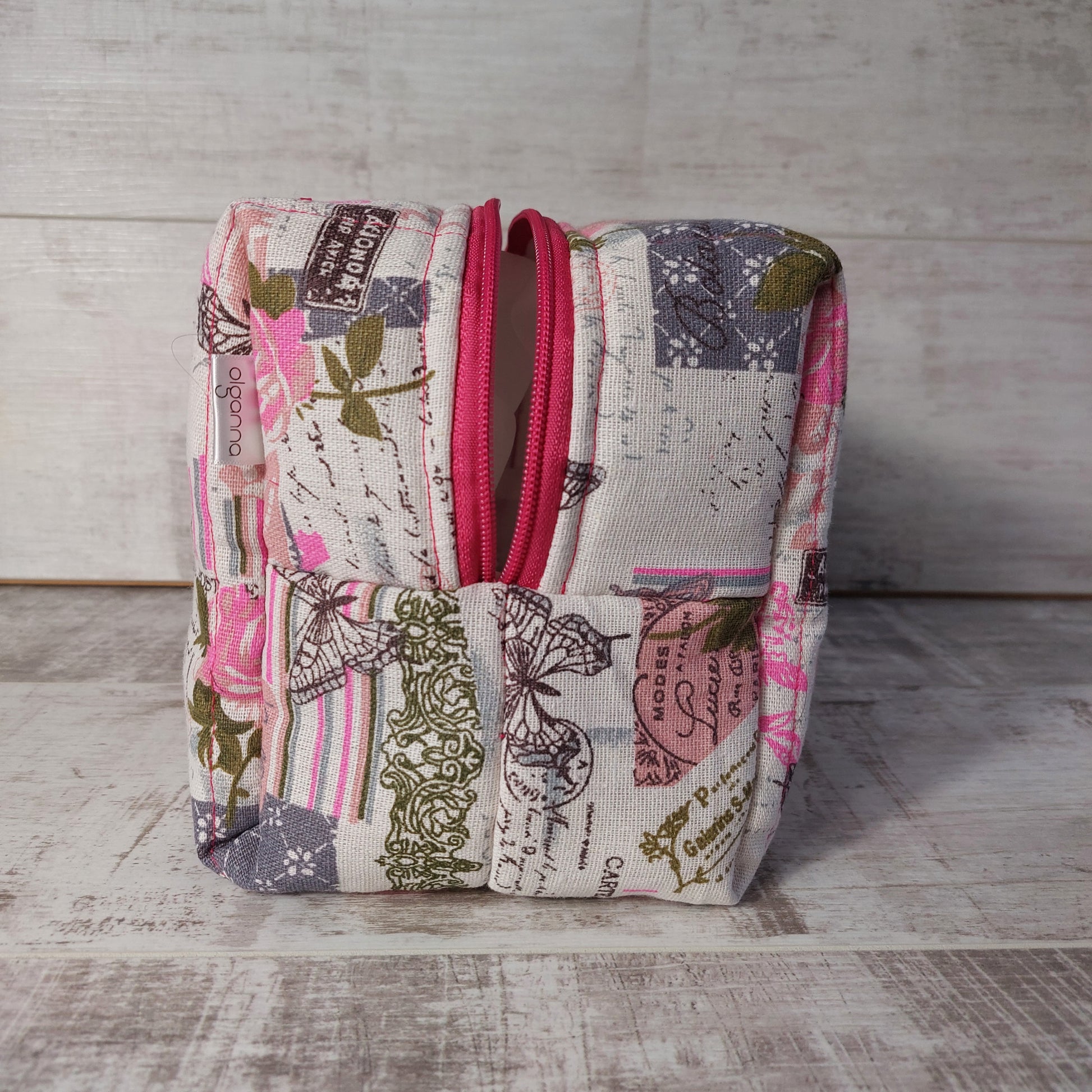 Pink and grey vintage rose and butterfly print quilted toiletries & makeup bag, end view showing dark pink zip opening.