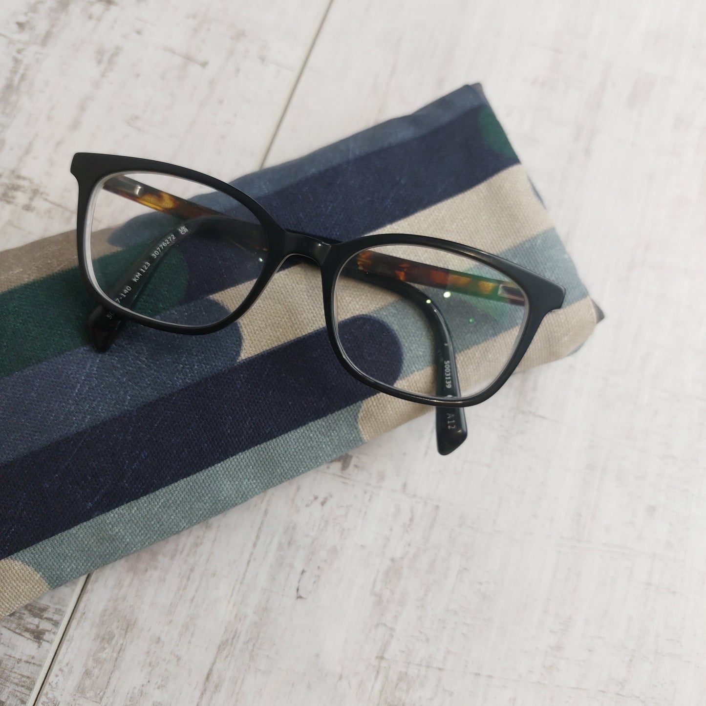 Padded glasses case in cool blue winter tones with glasses resting on top, by Olganna.