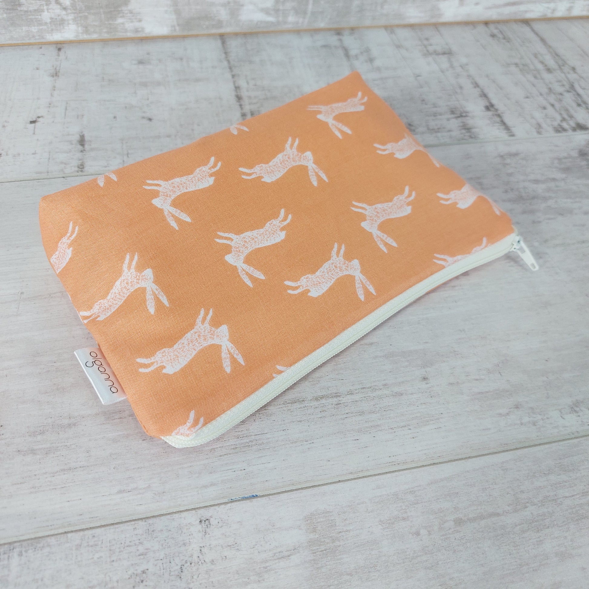 Pale gold bunny print makeup bag, lying down. 