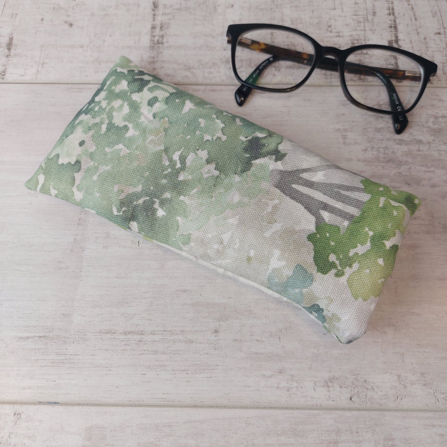 Green watercolour tree print glasses case pictured with glasses.