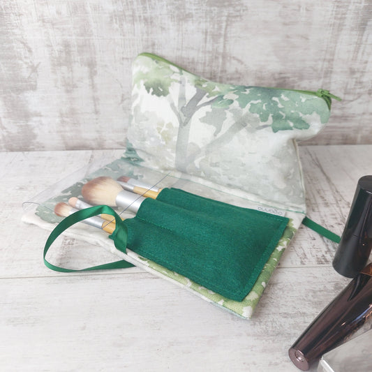 Forest green tree print makeup organiser open to reveal a green felt brushes pouch with a set of five bamboo-handled brushes.