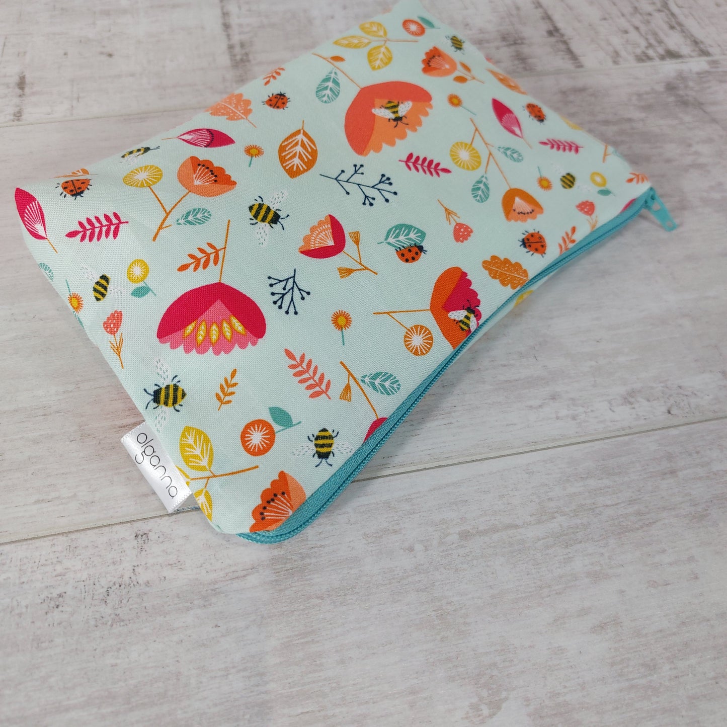 Spring floral and insect print makeup bag, lying down. 
