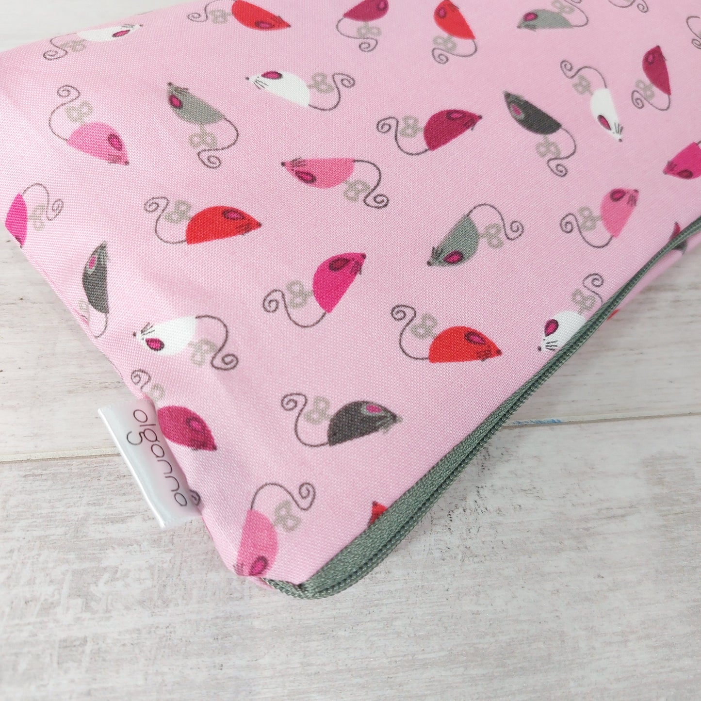 Close-up view of pink mice print makeup bag with side label saying 'olganna'. 