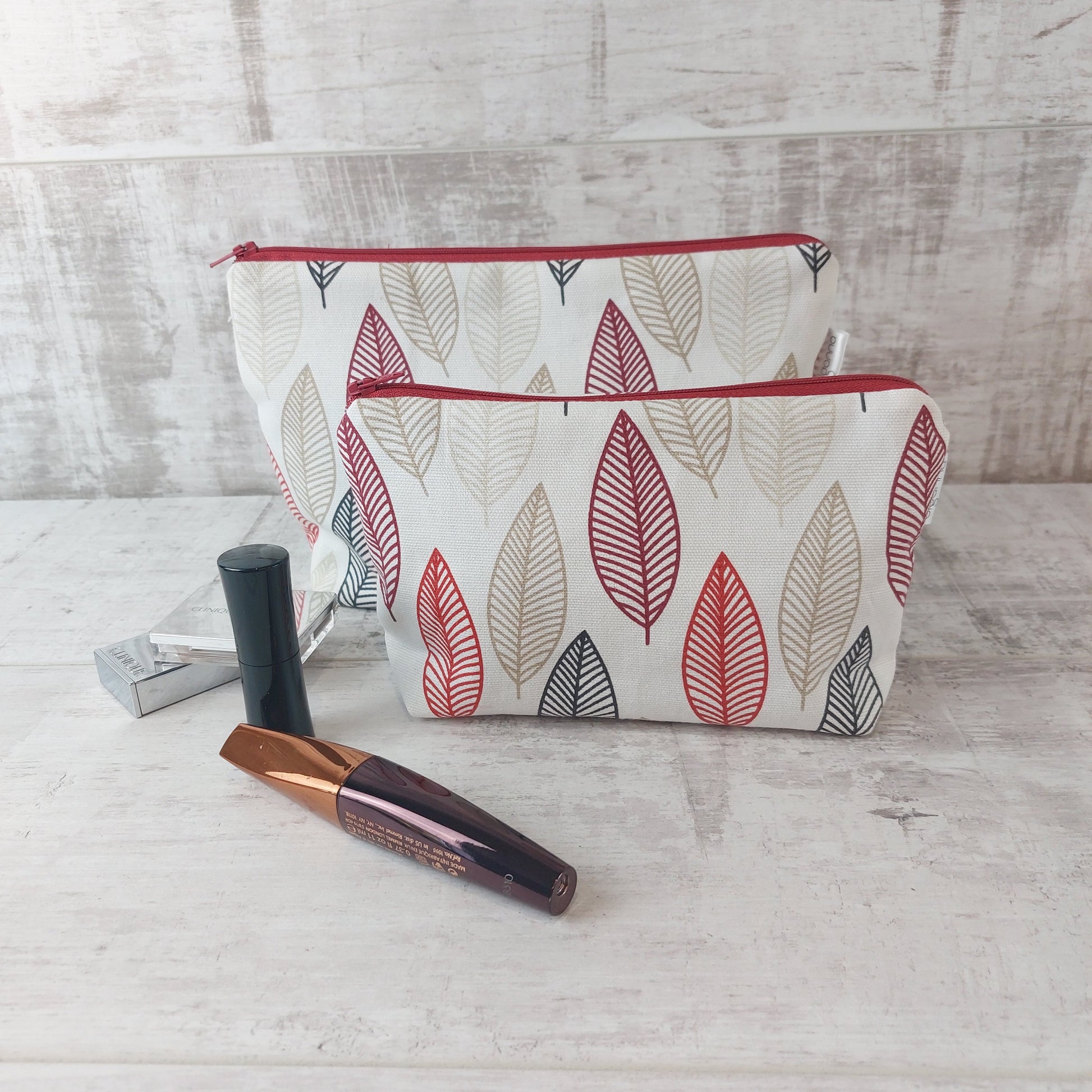 Small Scandi Autumn Leaves print pouch with larger pouch behind, pictured with beauty essentials.