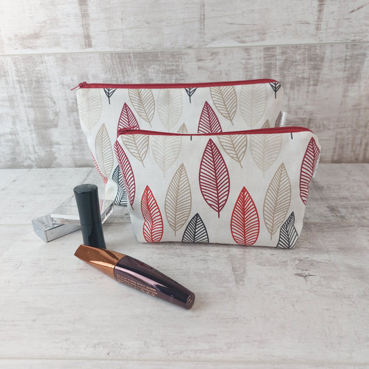 Small Scandi Autumn Leaves print pouch with larger pouch behind, pictured with beauty essentials.