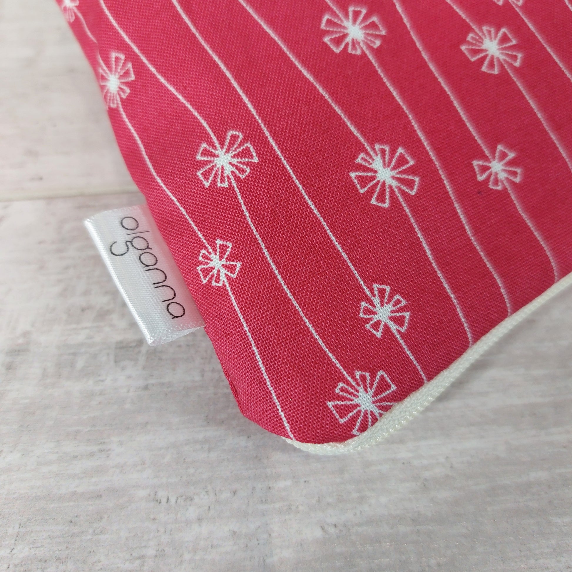 Close-up view of red and white flower print makeup bag with side label saying 'olganna'. 