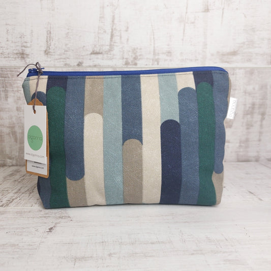 Toiletries zip bag in blue and winter tones stripe pattern with Olganna gift tag.