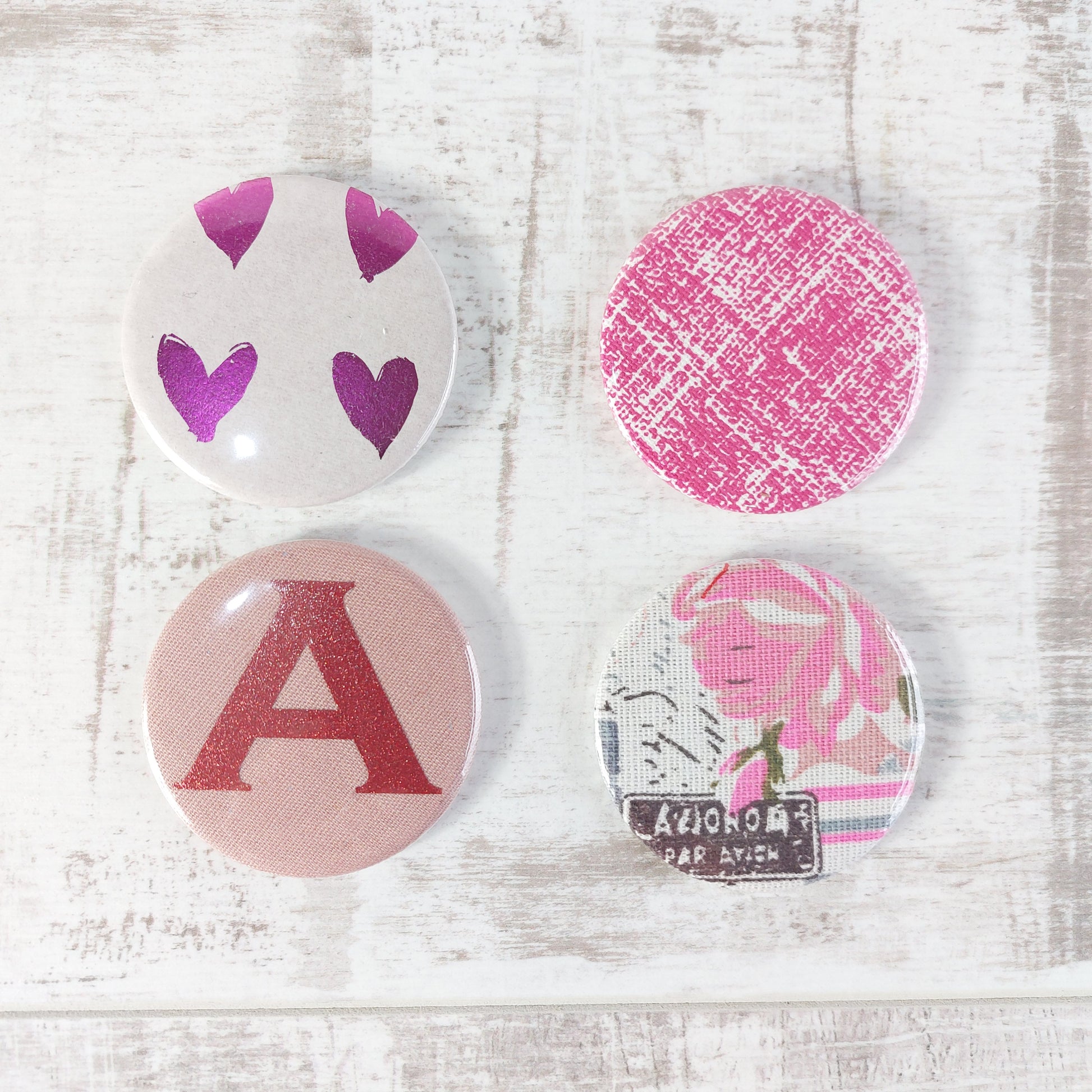 Four compact mirrors in two rows with different designs featuring pink tones.
