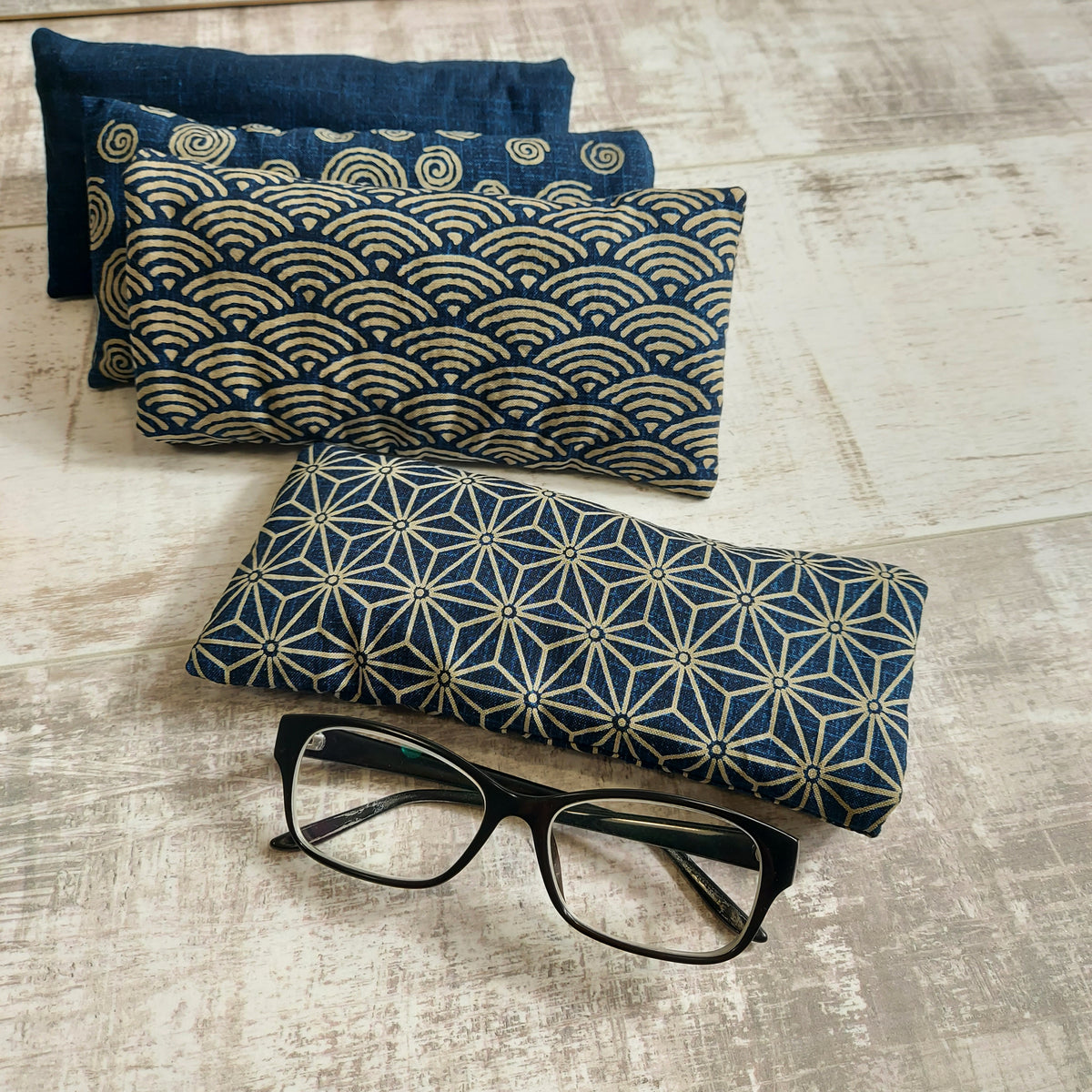 Four navy and taupe Japanese minimalist pattern glasses cases, pictured with glasses, by Olganna.